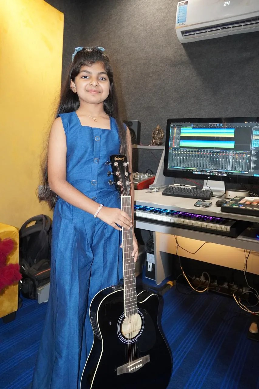 Young student holding a guitar beside the CloudStudio108 production desk