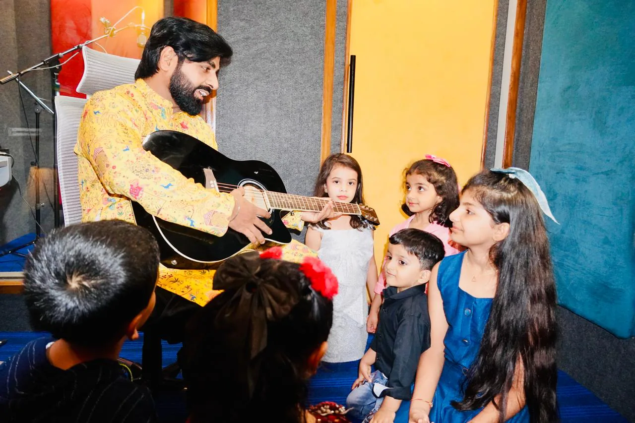 Music instructor teaching guitar to a group of young academy students at CloudStudio108