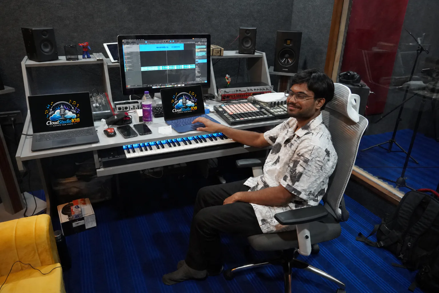 CloudStudio108 sound engineer working at the full recording console with the studio logo displayed on both laptops