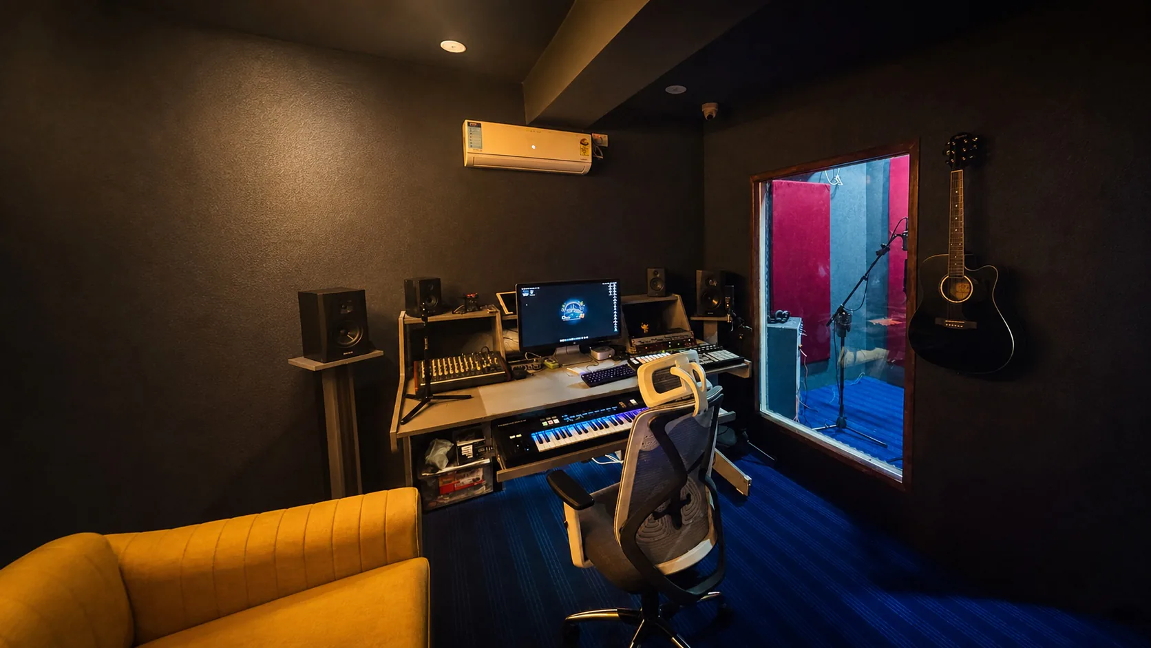 Enhanced wide view of the CloudStudio108 production desk, studio monitors, keyboard, guitar, and vocal booth