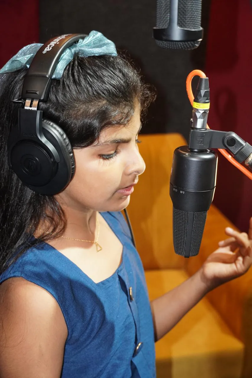 Close portrait of the young vocalist recording with headphones and a studio microphone