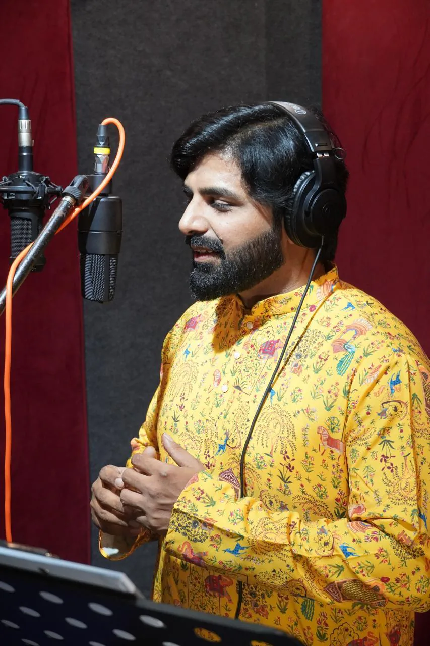 Male vocalist recording with headphones and multiple studio microphones