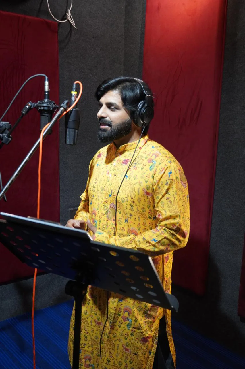 Portrait of a vocalist in a yellow kurta performing with headphones and a music stand
