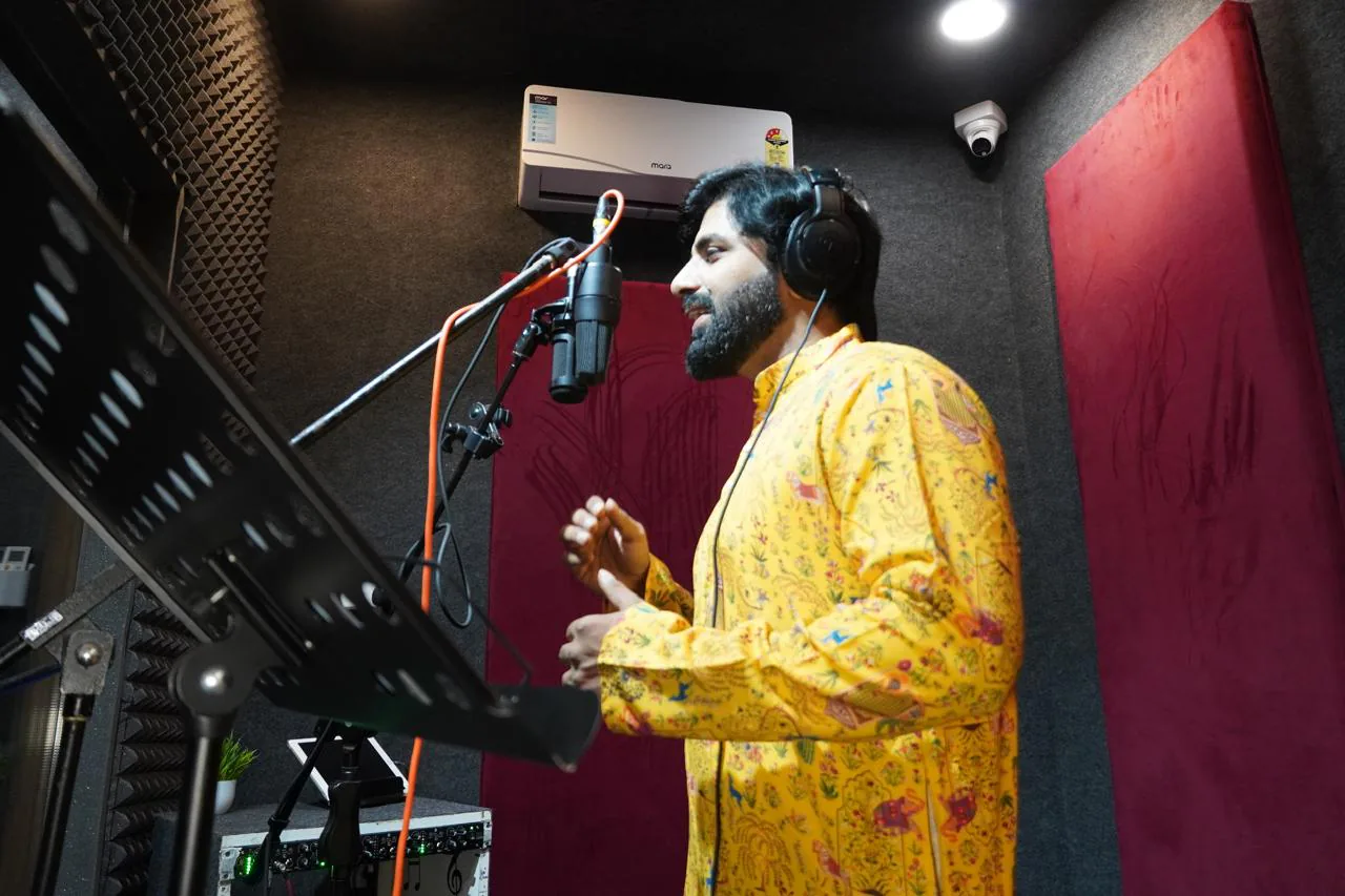 Side-angle view of a vocalist recording in the spacious treated studio booth